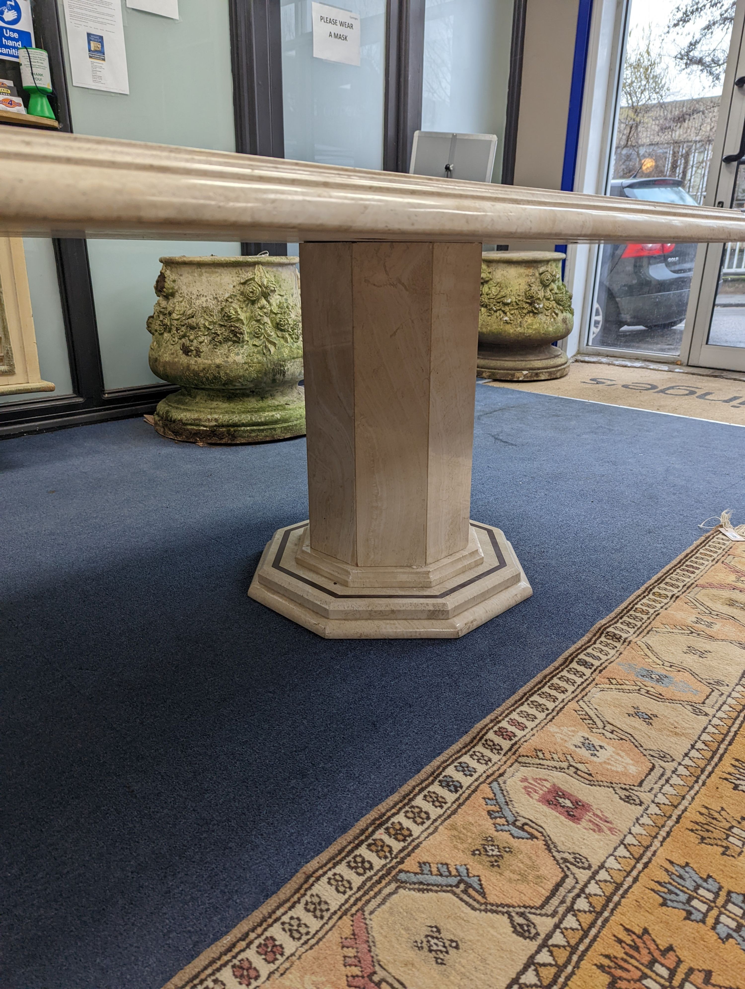 A Travertine marble dining table of elongated ocgtagonal form on twin octagonal column supports, length 260cm, depth 120cm, height 74cm